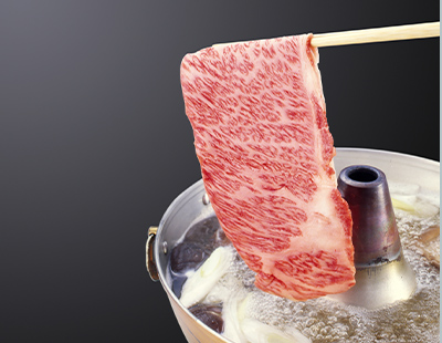 箸で持った霜降り和牛をしゃぶしゃぶ鍋へ下ろす様子の写真